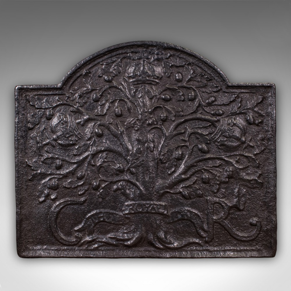 A rectangular dark cast iron fireback with an arched central top featuring a raised relief of the Royal Oak tree motif.