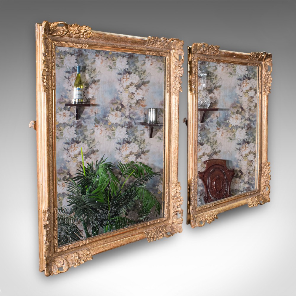 A pair of large rectangular Regency style wall mirrors with ornate gold giltwood frames and floral corner embellishments.