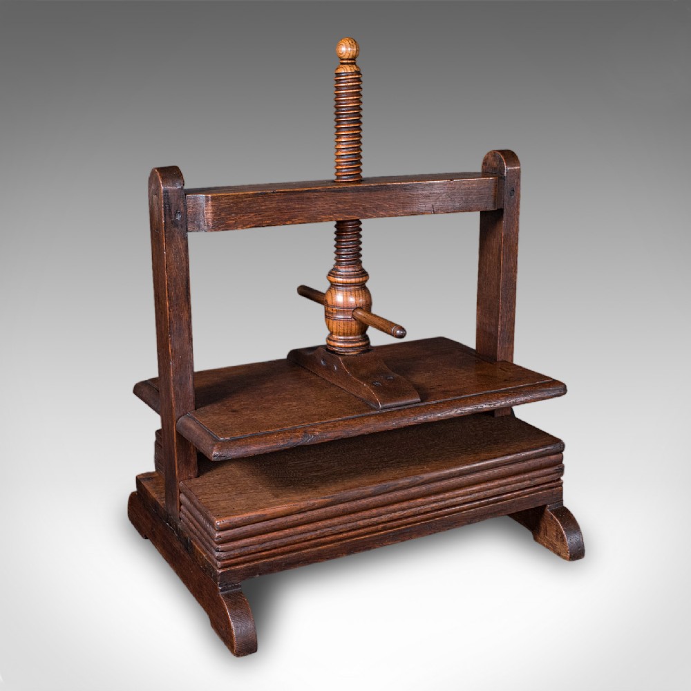 A dark oak Georgian flower press with a central turned wooden screw mechanism and rectangular pressing boards.
