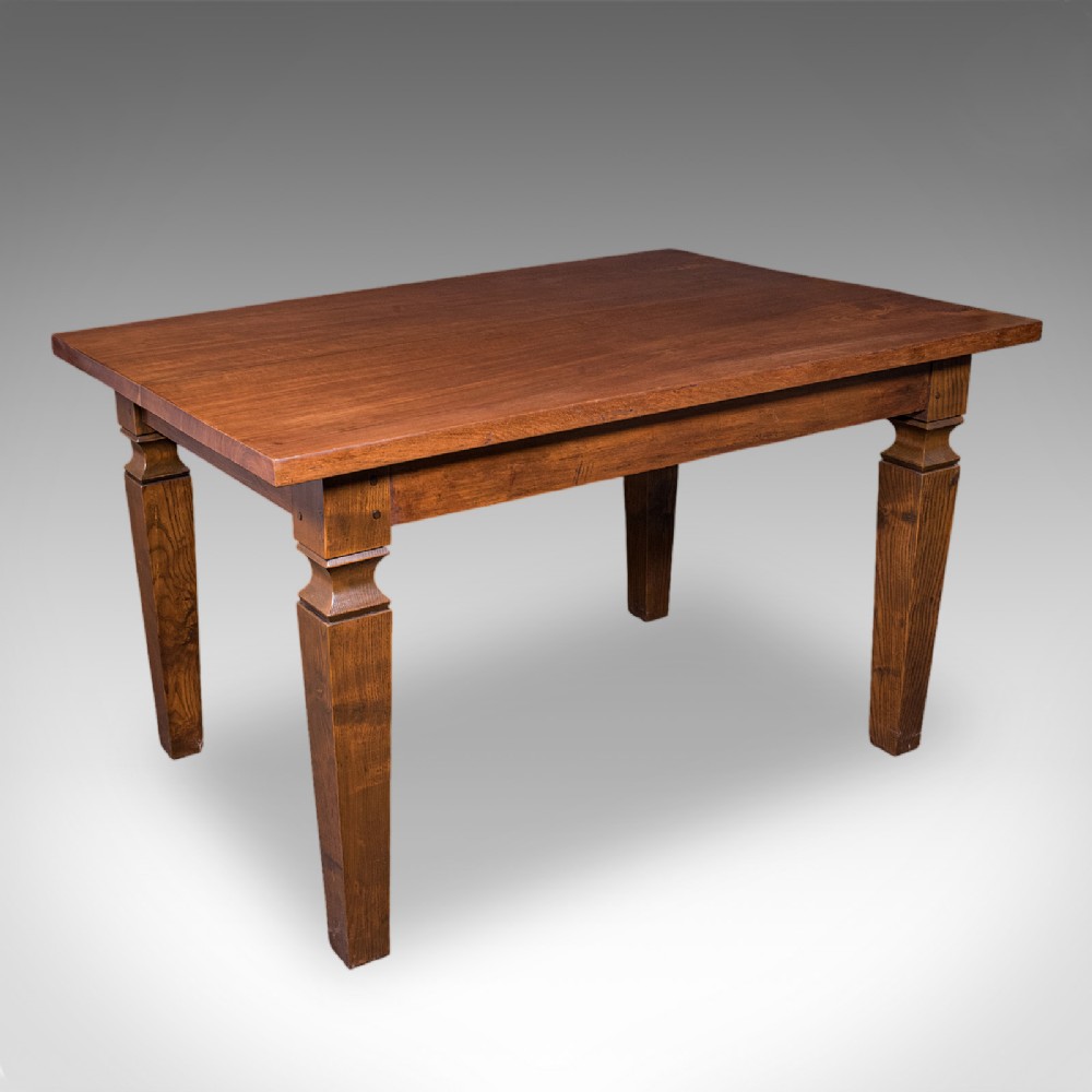 An Edwardian rectangular walnut dining table featuring square tapered legs with shoulder moulding and a smooth wood top.
