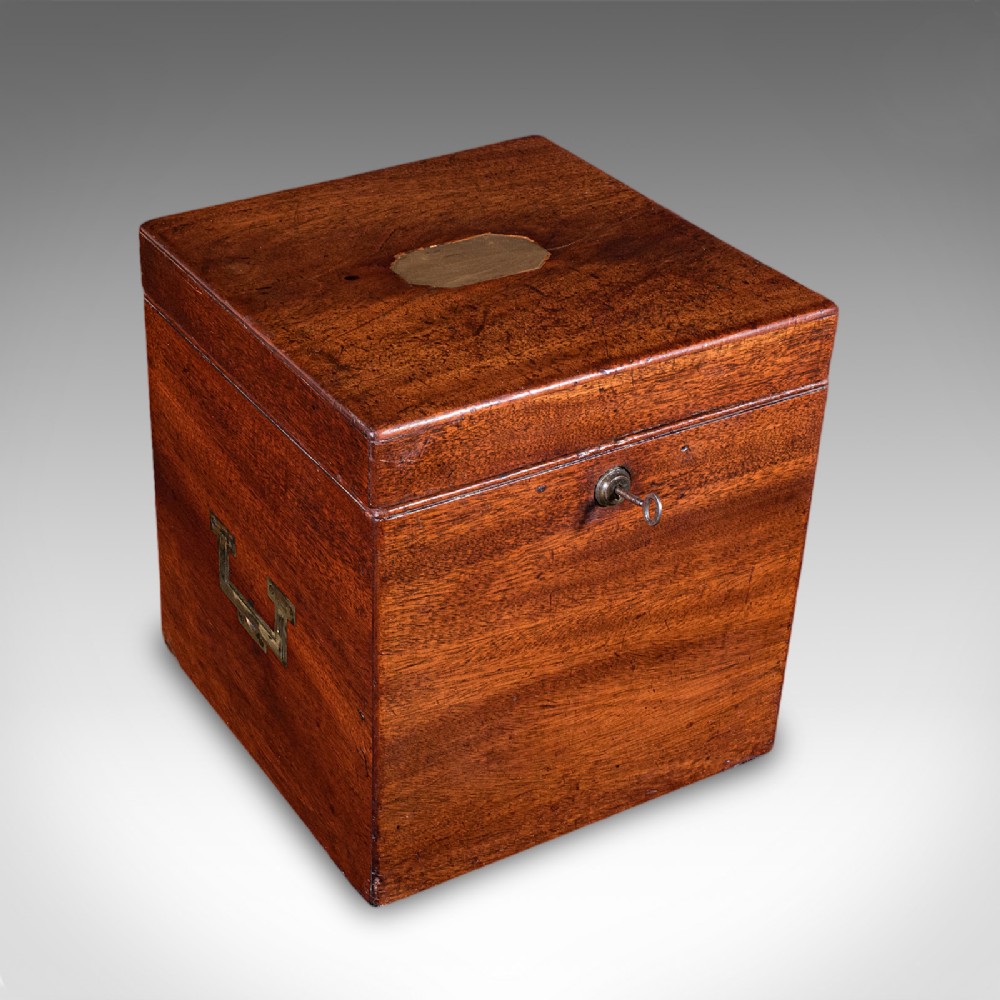 A Georgian mahogany four-decanter storage box featuring a brass top plaque, side carrying handles, and a key inserted in the front lock.