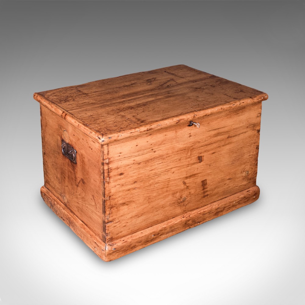 An antique rectangular Victorian pine carriage chest with a hinged lid, side iron carry handles, and a lower plinth base.