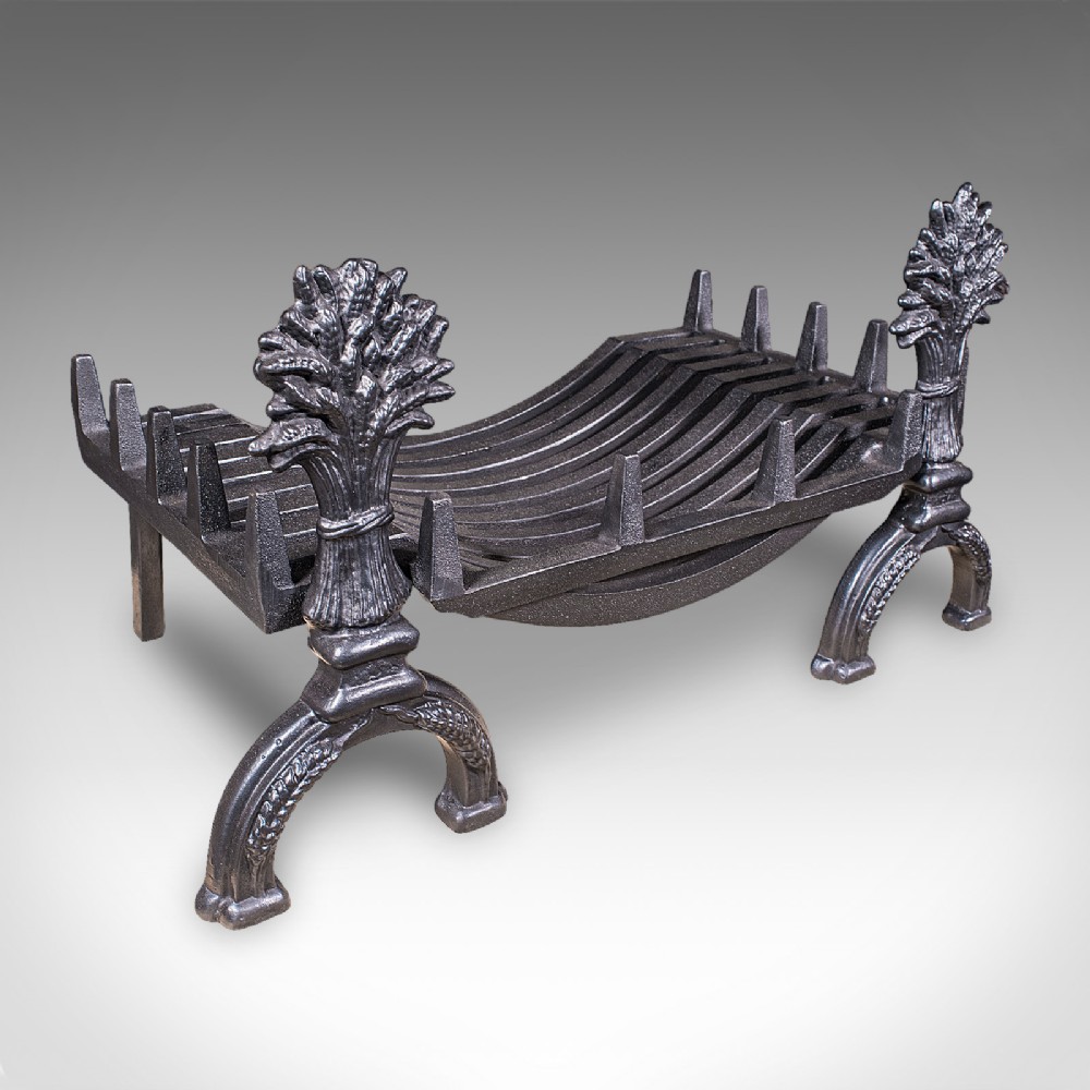 Victorian cast iron fire basket featuring curved grate bars and integrated front andirons decorated with wheat sheaf motifs.