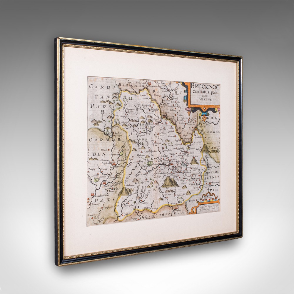 A framed 1607 hand-coloured antique map of Brecknoc set within a cream mount and a dark frame with gold trim.
