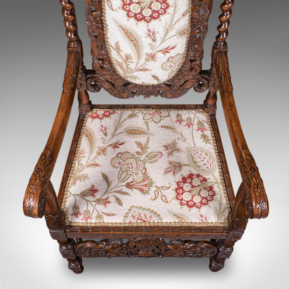 A pair of carved dark oak armchairs featuring barley twist uprights, intricate cherub carvings, and cream floral tapestry upholstery with red fringe trim. View VII