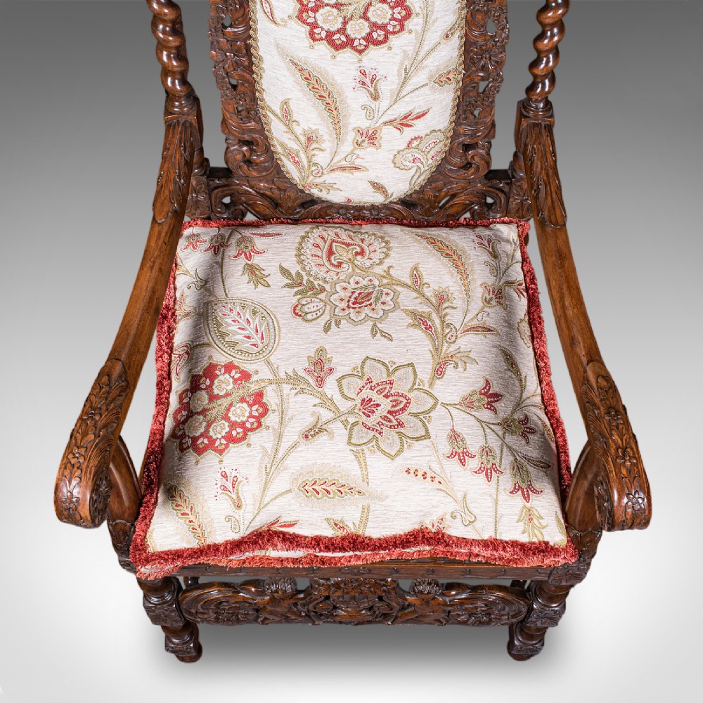 A pair of carved dark oak armchairs featuring barley twist uprights, intricate cherub carvings, and cream floral tapestry upholstery with red fringe trim. View VIII