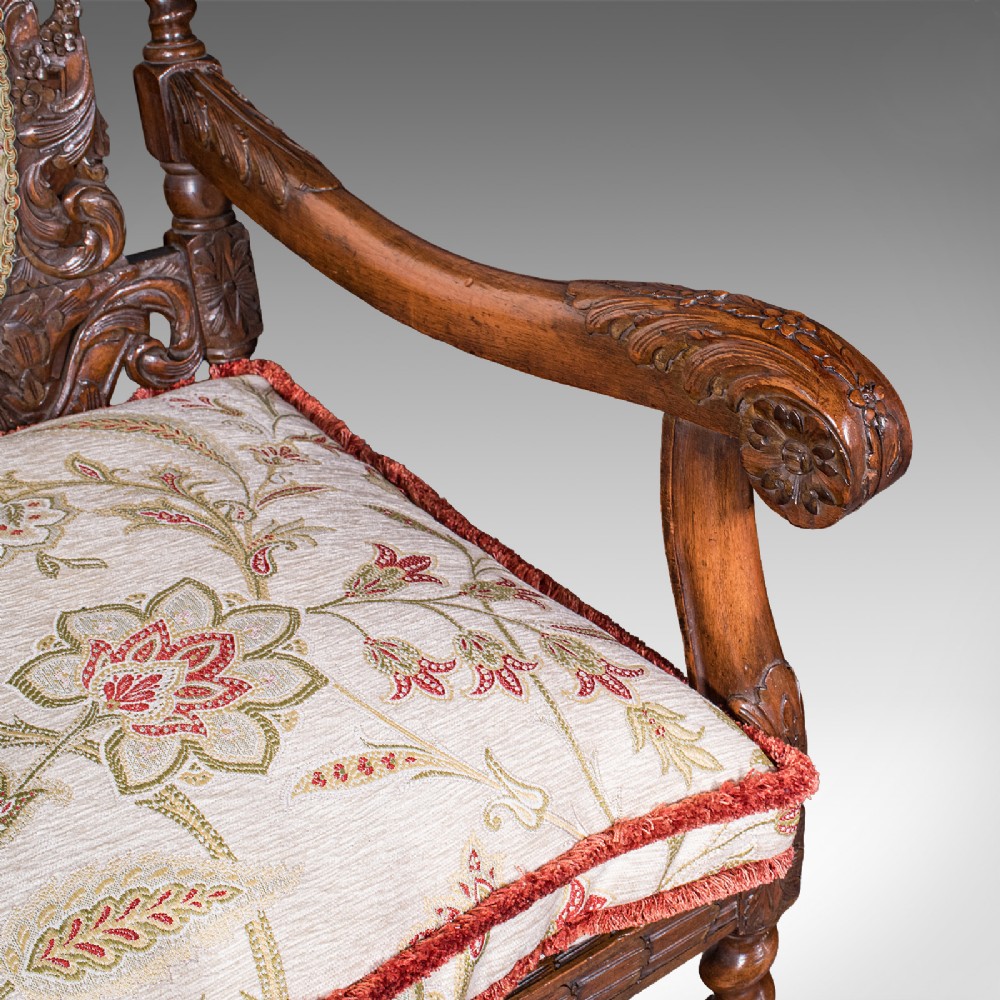 A pair of carved dark oak armchairs featuring barley twist uprights, intricate cherub carvings, and cream floral tapestry upholstery with red fringe trim. View XI