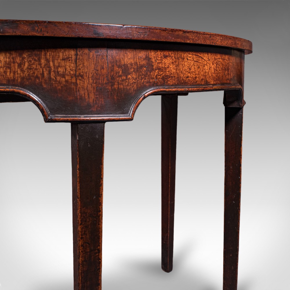 An antique dark mahogany demi-lune console table featuring tapered legs and a curved frieze. View VIII