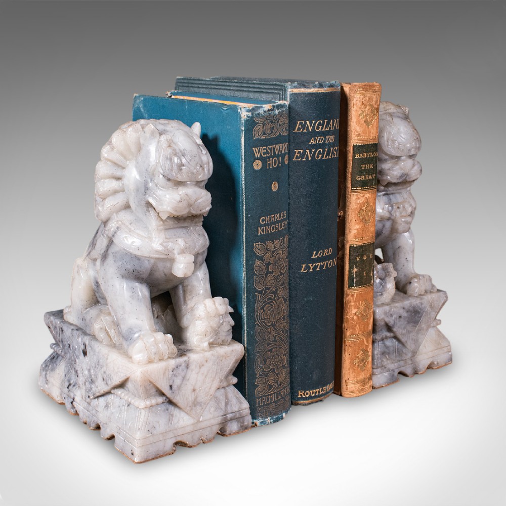 A pair of hand-carved mottled grey soapstone guardian lion bookends mounted on carved pedestals. View II