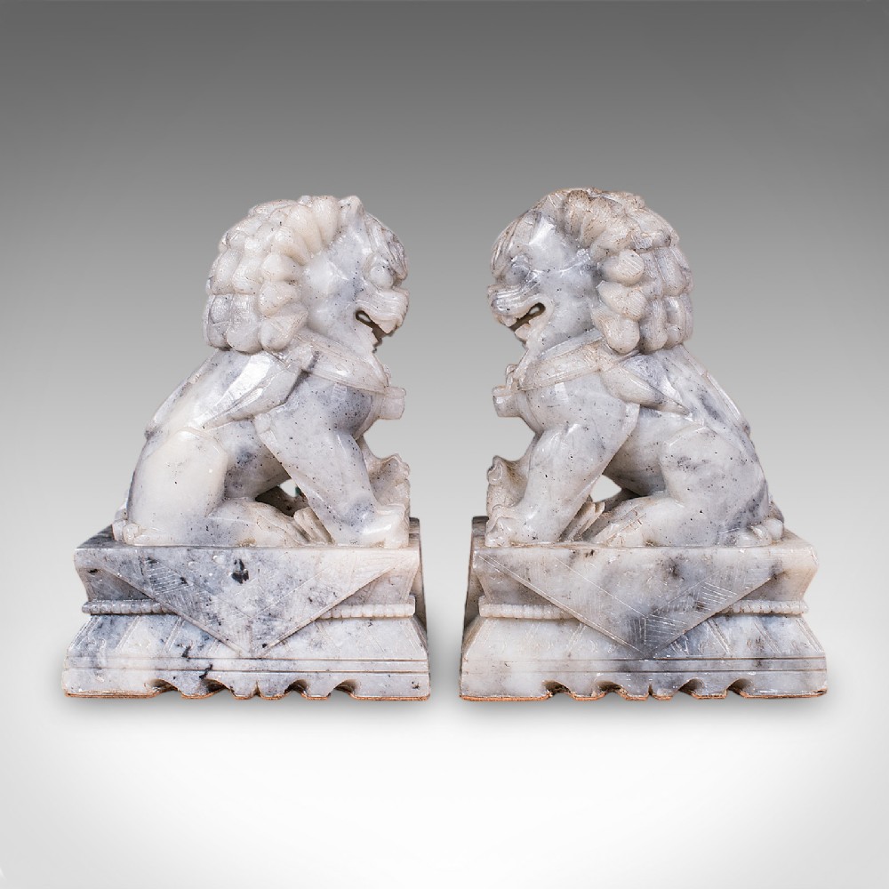 A pair of hand-carved mottled grey soapstone guardian lion bookends mounted on carved pedestals. View IV