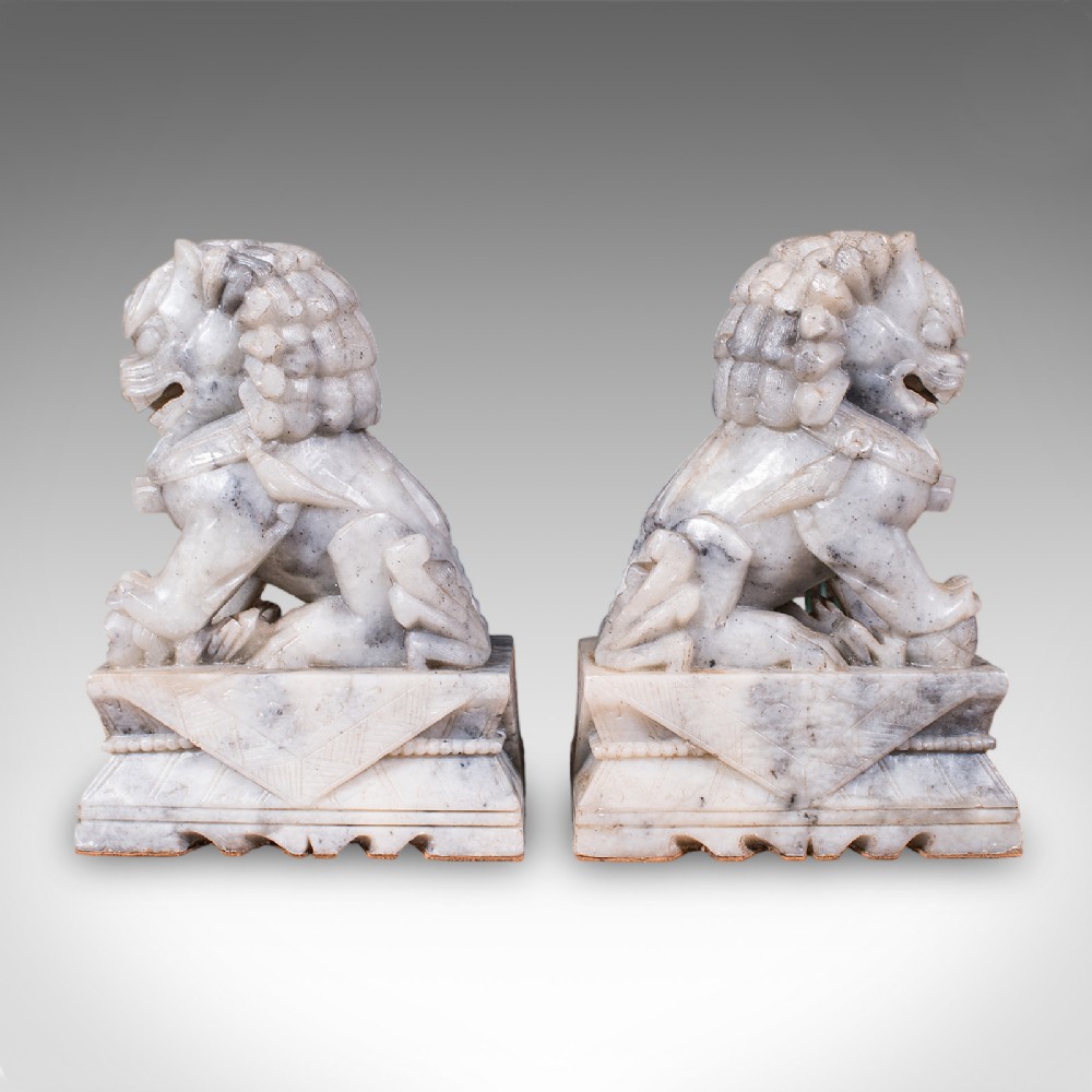 A pair of hand-carved mottled grey soapstone guardian lion bookends mounted on carved pedestals. View V