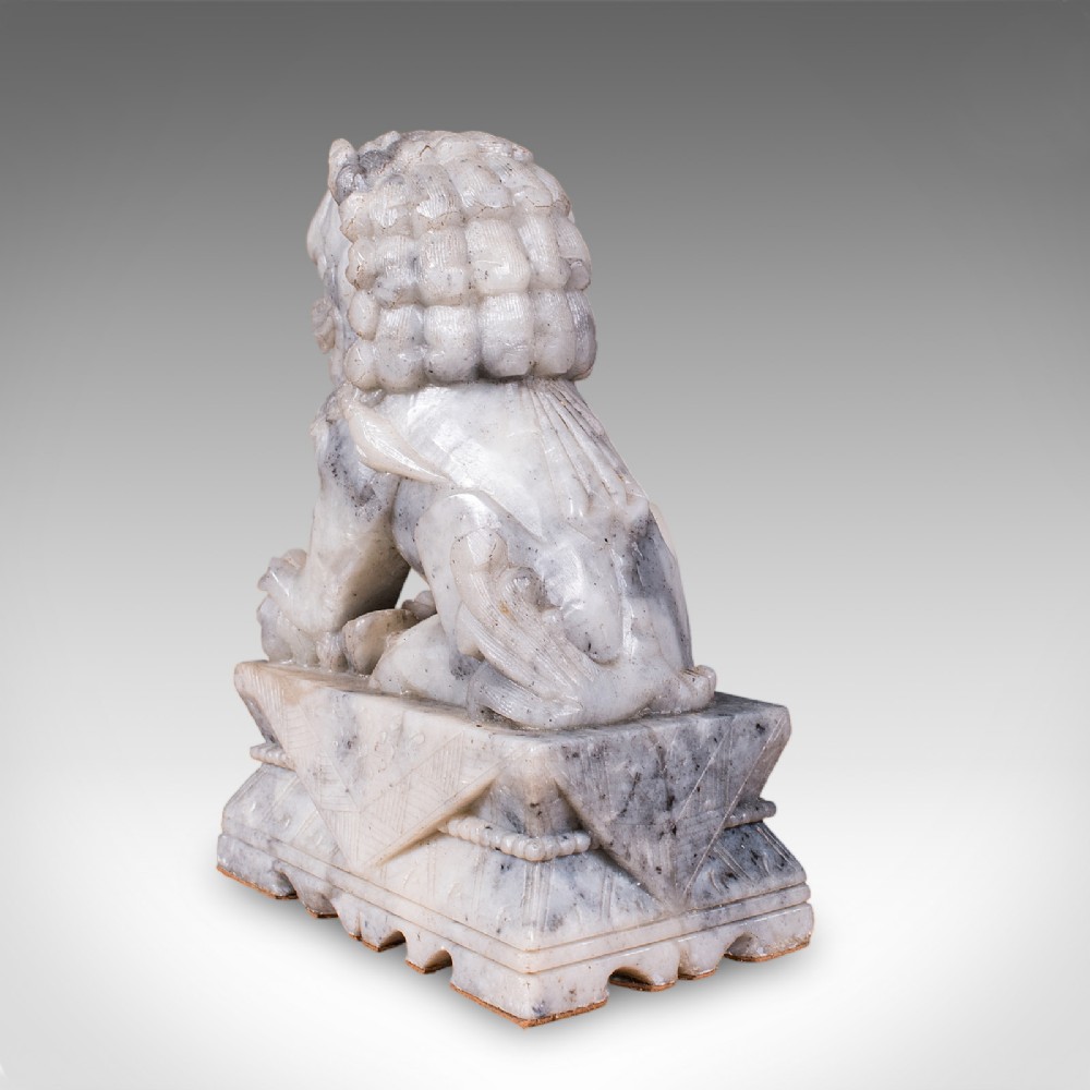 A pair of hand-carved mottled grey soapstone guardian lion bookends mounted on carved pedestals. View VII