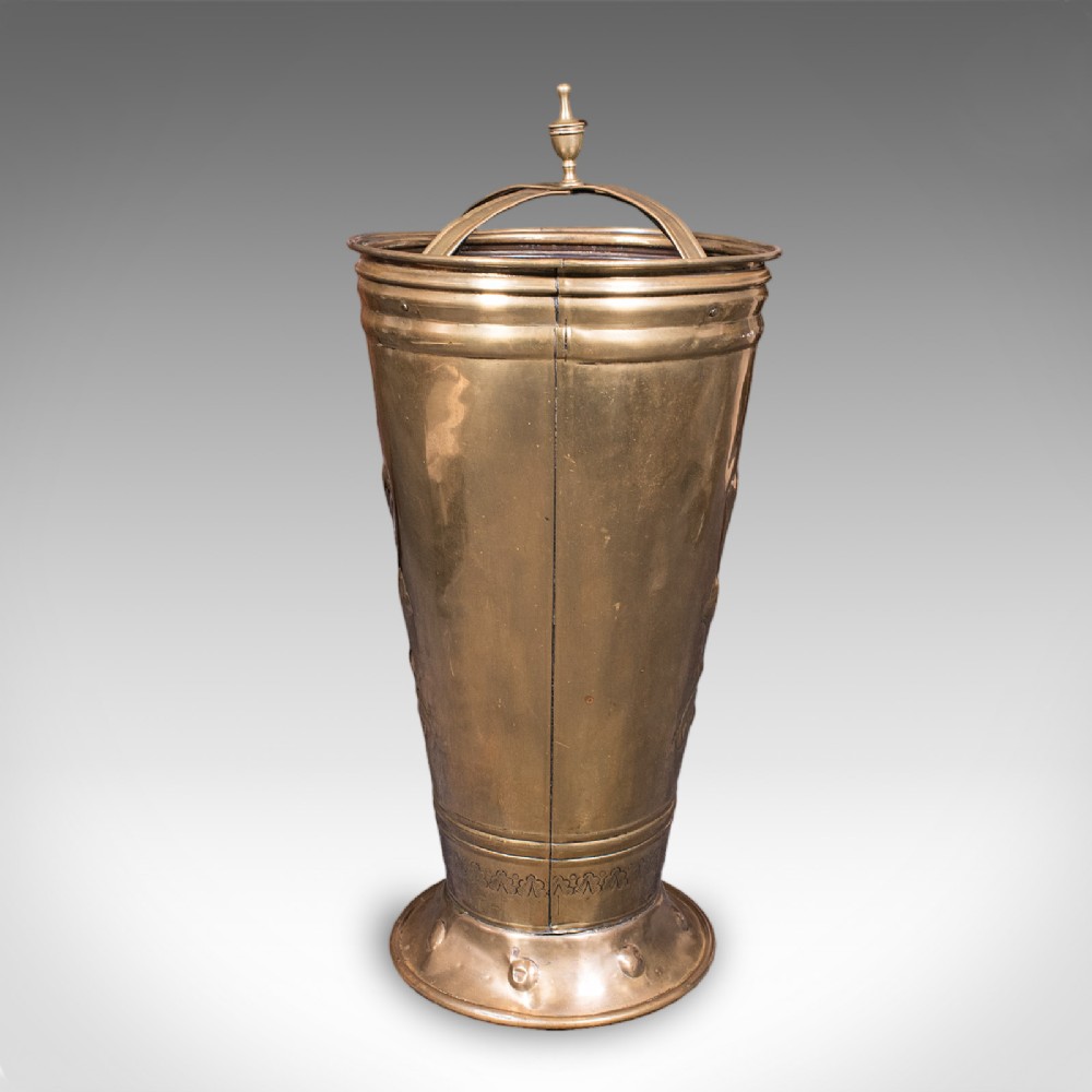 An antique tapered brass umbrella stand featuring embossed Dutch windmill motifs, top dividers with a turned brass finial, and a flared base. View IV