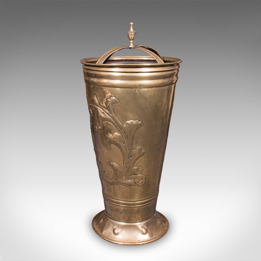An antique tapered brass umbrella stand featuring embossed Dutch windmill motifs, top dividers with a turned brass finial, and a flared base. View V