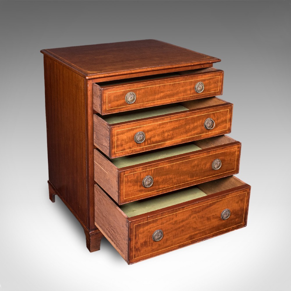 An antique mahogany small chest of drawers featuring four graduated inlaid drawers, circular brass ring pull handles, and bracket feet. View II