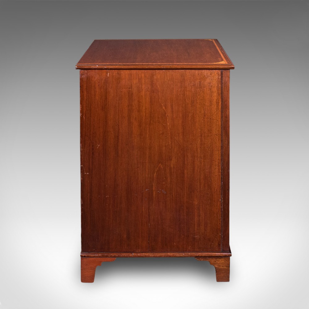An antique mahogany small chest of drawers featuring four graduated inlaid drawers, circular brass ring pull handles, and bracket feet. View IV