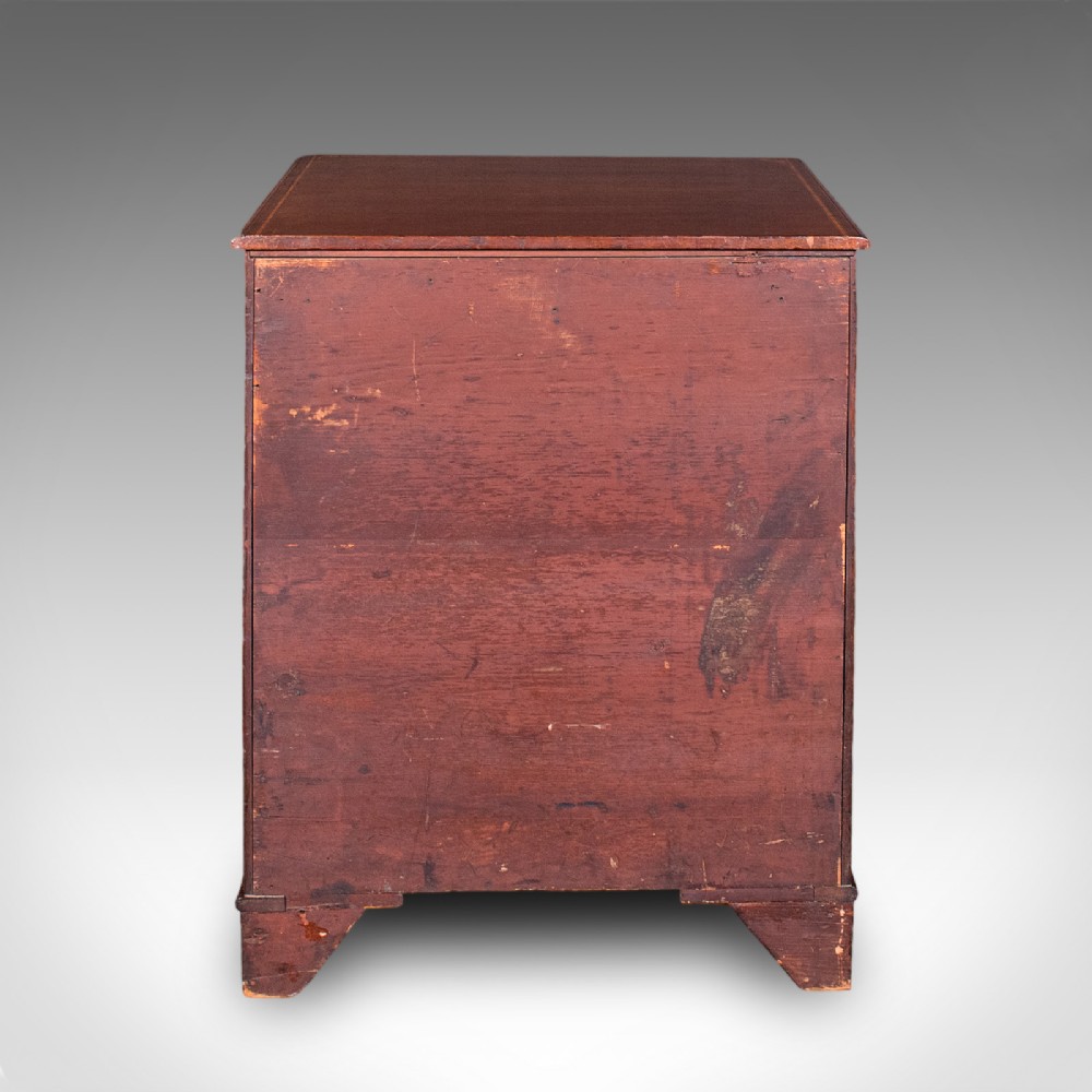 An antique mahogany small chest of drawers featuring four graduated inlaid drawers, circular brass ring pull handles, and bracket feet. View V