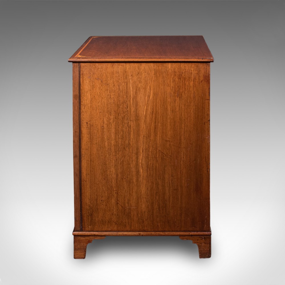 An antique mahogany small chest of drawers featuring four graduated inlaid drawers, circular brass ring pull handles, and bracket feet. View VI