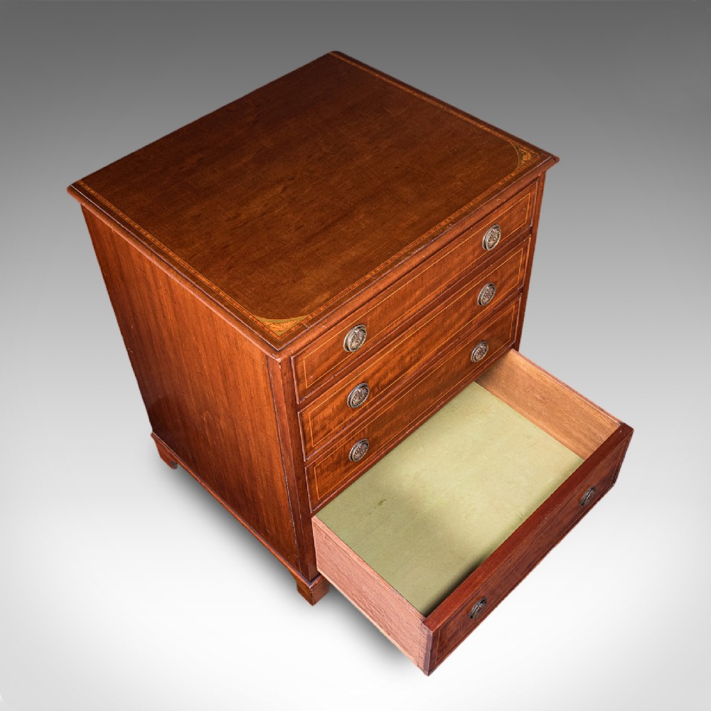 An antique mahogany small chest of drawers featuring four graduated inlaid drawers, circular brass ring pull handles, and bracket feet. View VIII