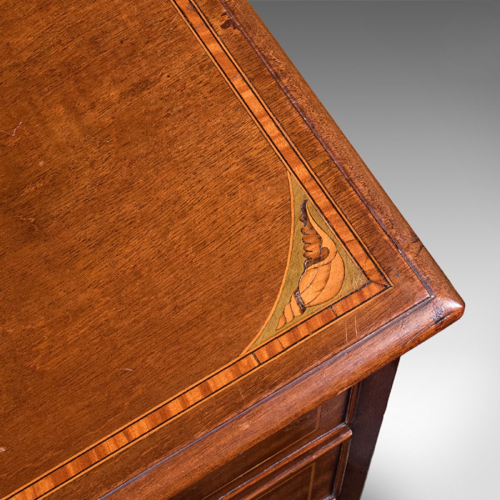 An antique mahogany small chest of drawers featuring four graduated inlaid drawers, circular brass ring pull handles, and bracket feet. View IX