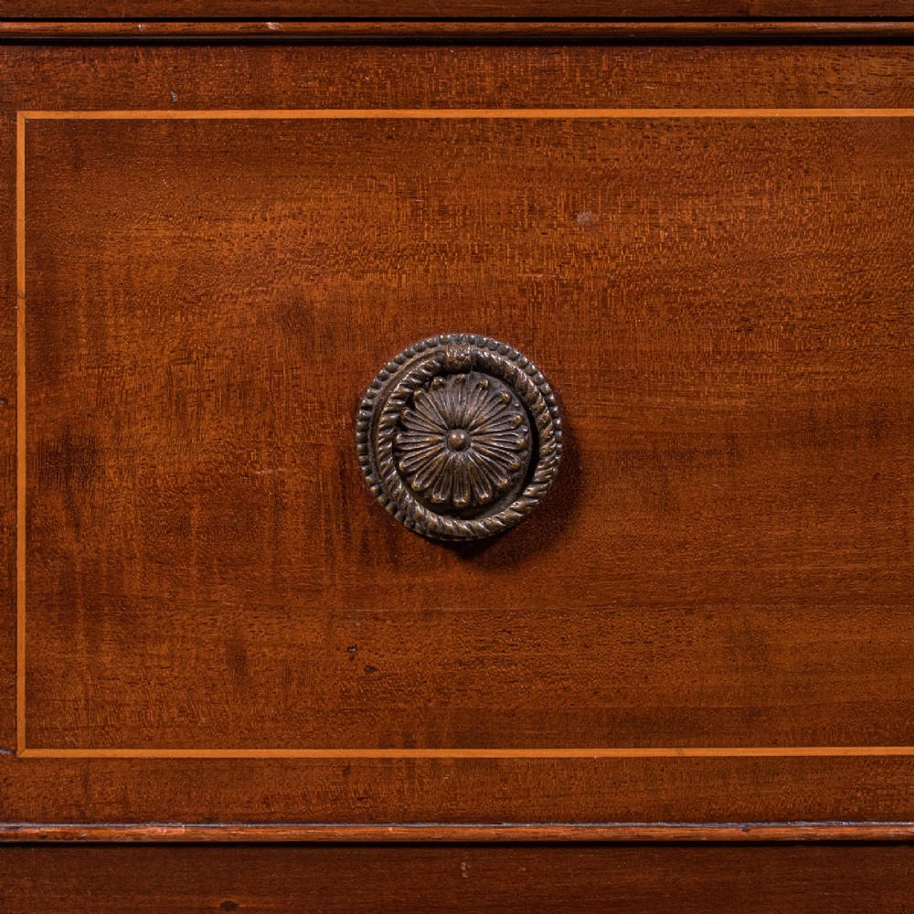 An antique mahogany small chest of drawers featuring four graduated inlaid drawers, circular brass ring pull handles, and bracket feet. View XI
