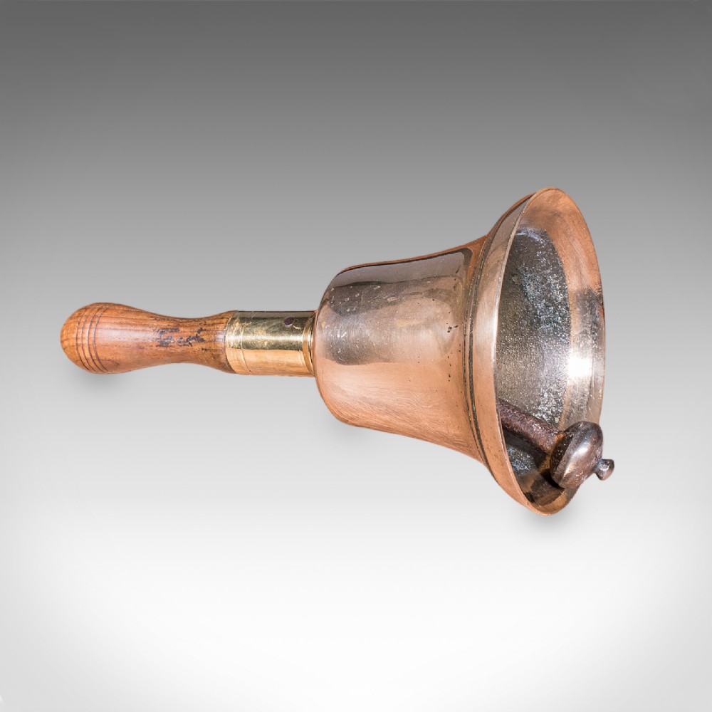Victorian hand bell featuring a polished brass bell body with a turned beech handle set on a circular wooden stand. View III