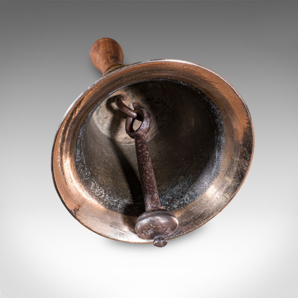 Victorian hand bell featuring a polished brass bell body with a turned beech handle set on a circular wooden stand. View XI