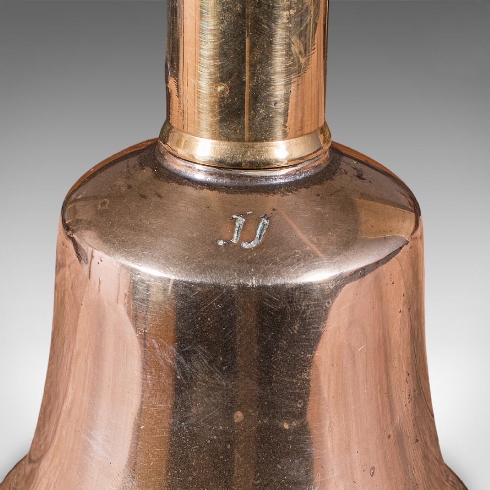 Victorian hand bell featuring a polished brass bell body with a turned beech handle set on a circular wooden stand. View XII