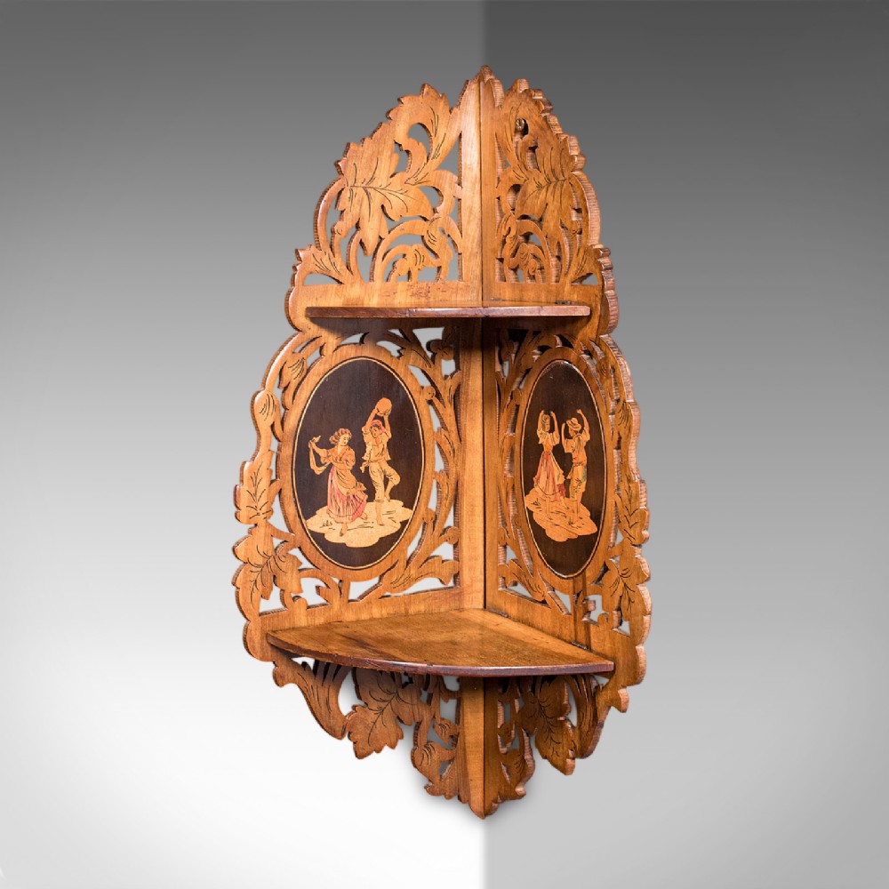 A Victorian Italian walnut corner display shelf featuring two tiers, openwork foliage fretwork borders, and oval marquetry panels depicting folk dancers. View IV