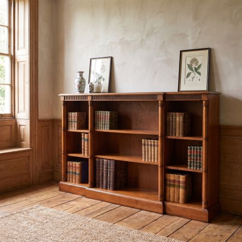 fig 1. A low Regency style mahogany breakfront open bookcase featuring three shelving sections separated by reeded pilasters.