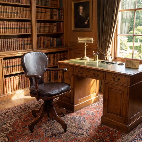 fig 1. A late Victorian mahogany revolving desk chair upholstered in dark brown leather with turned arm supports and a quadruped base on castors.