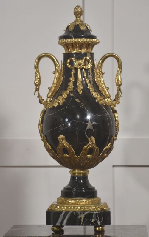 fig 1. A black veined-marble urn with two handles and gilt-metal mounts resting on a matching cylindrical black marble pedestal with a Corinthian capital.