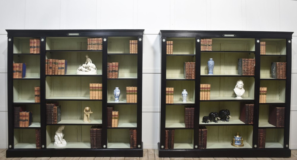 A pair of large ebonised open bookcases featuring three vertical shelving sections with pale green painted interiors and circular ceramic plaque detailing. View II