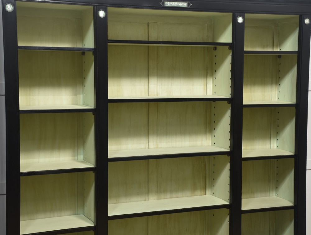 A pair of large ebonised open bookcases featuring three vertical shelving sections with pale green painted interiors and circular ceramic plaque detailing. View III