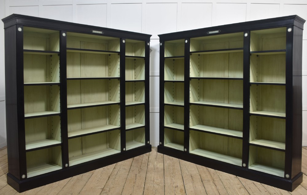 A pair of large ebonised open bookcases featuring three vertical shelving sections with pale green painted interiors and circular ceramic plaque detailing. View VIII