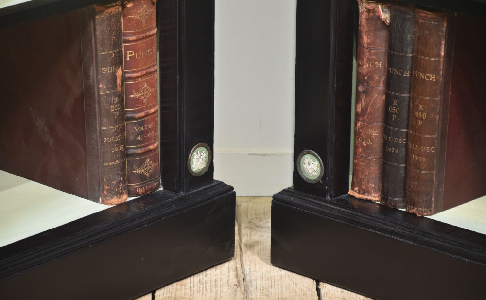 A pair of large ebonised open bookcases featuring three vertical shelving sections with pale green painted interiors and circular ceramic plaque detailing. View XIX