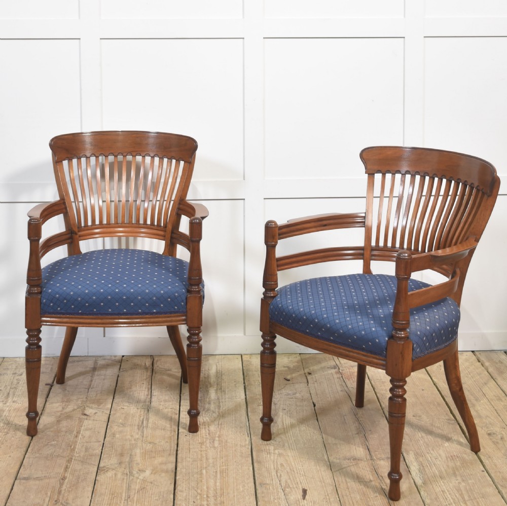 A pair of mahogany elbow chairs featuring slatted curved backs, turned front legs, and blue patterned upholstered seats. View IX