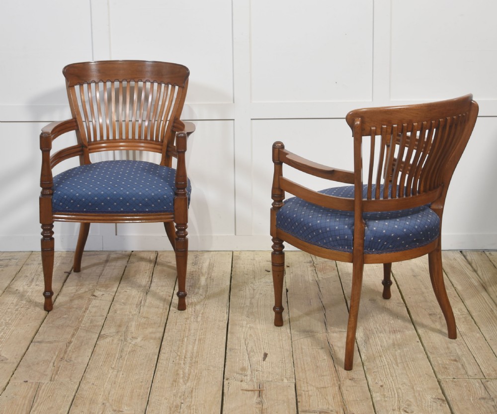 A pair of mahogany elbow chairs featuring slatted curved backs, turned front legs, and blue patterned upholstered seats. View XII