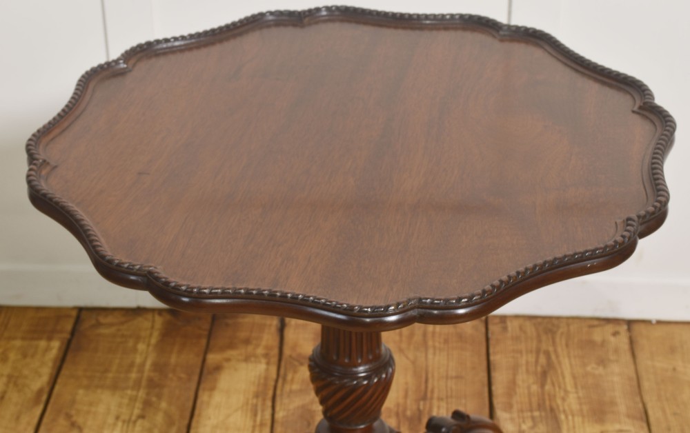 A dark carved mahogany tripod occasional table featuring a scalloped piecrust top, fluted central pedestal, and carved cabriole legs. View V