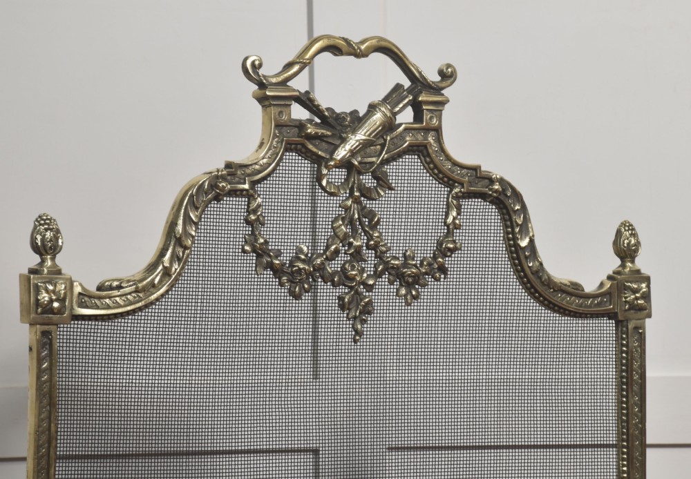 An ornate late 19th-century French gilt brass fire screen featuring a wire mesh panel decorated with a central urn motif, floral swags, and a top crest with a quiver and torch. View III
