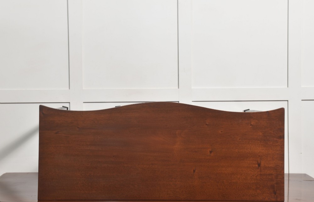 An Edwardian mahogany bow-fronted side table featuring four drawers with brass ring handles and slender fluted legs ending in spade feet. View VIII