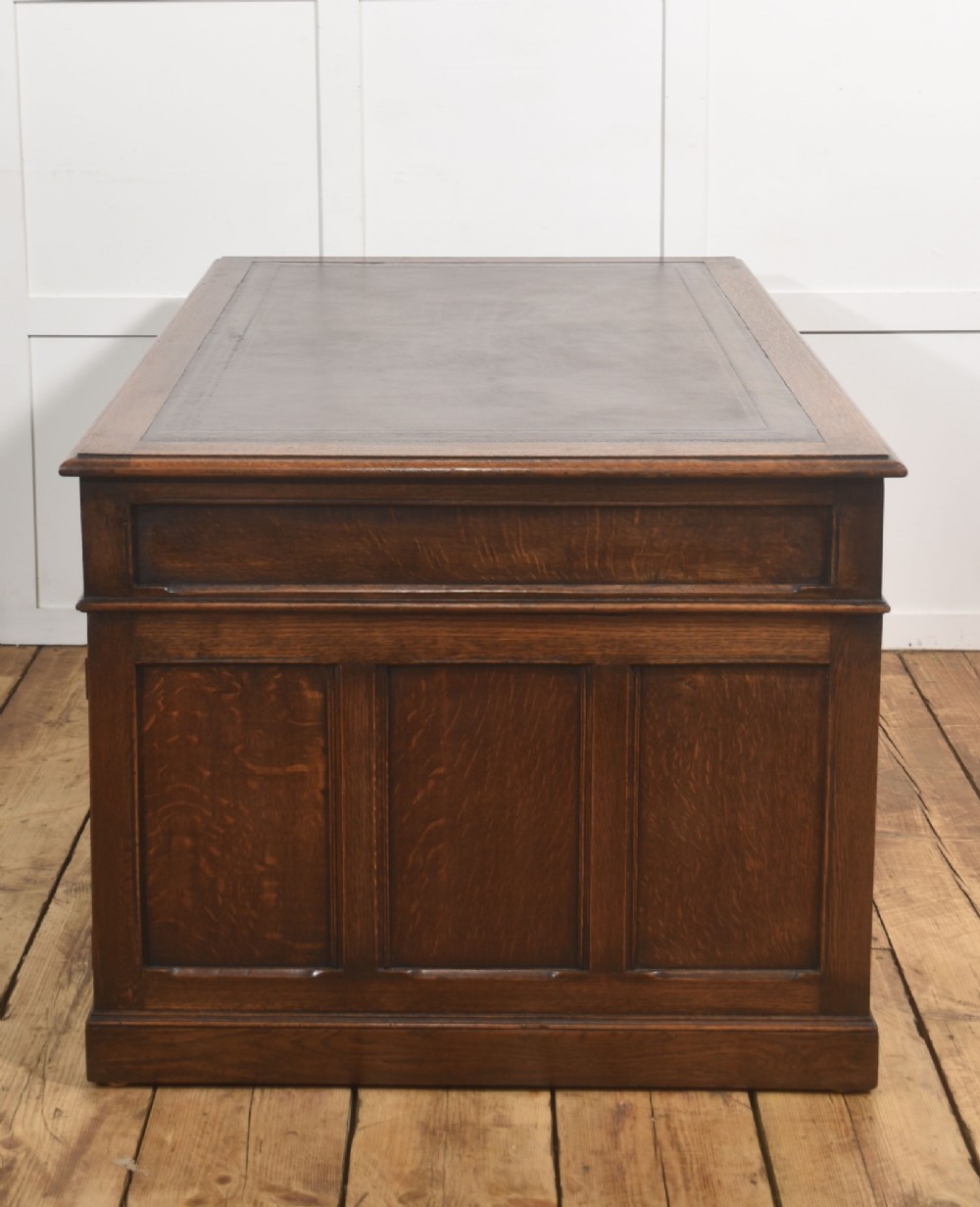A double-pedestal antique oak partners desk featuring geometric drawer mouldings and an inset brown leather writing top. View III