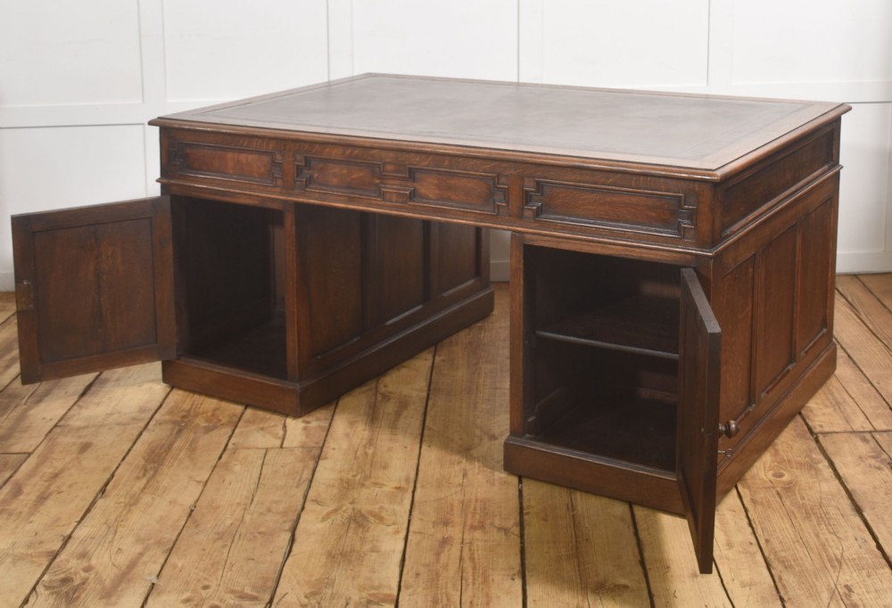 A double-pedestal antique oak partners desk featuring geometric drawer mouldings and an inset brown leather writing top. View IV
