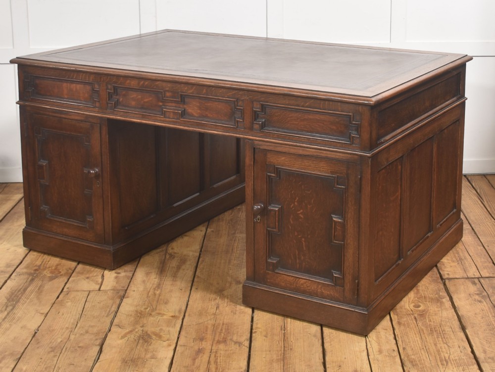 A double-pedestal antique oak partners desk featuring geometric drawer mouldings and an inset brown leather writing top. View V
