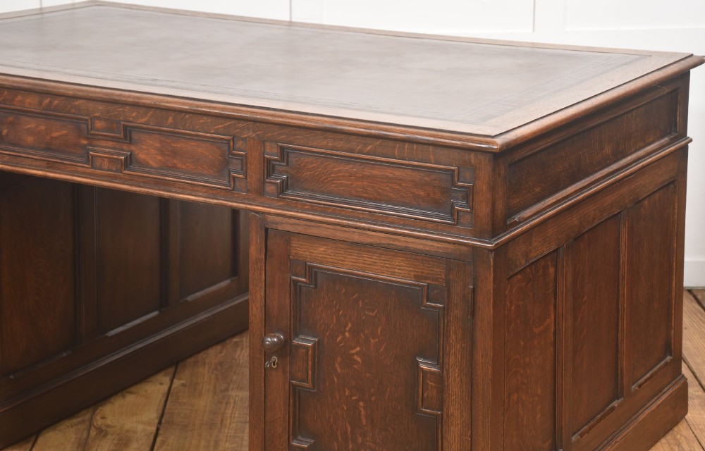 A double-pedestal antique oak partners desk featuring geometric drawer mouldings and an inset brown leather writing top. View VI