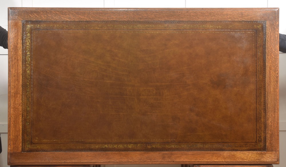 A double-pedestal antique oak partners desk featuring geometric drawer mouldings and an inset brown leather writing top. View VIII