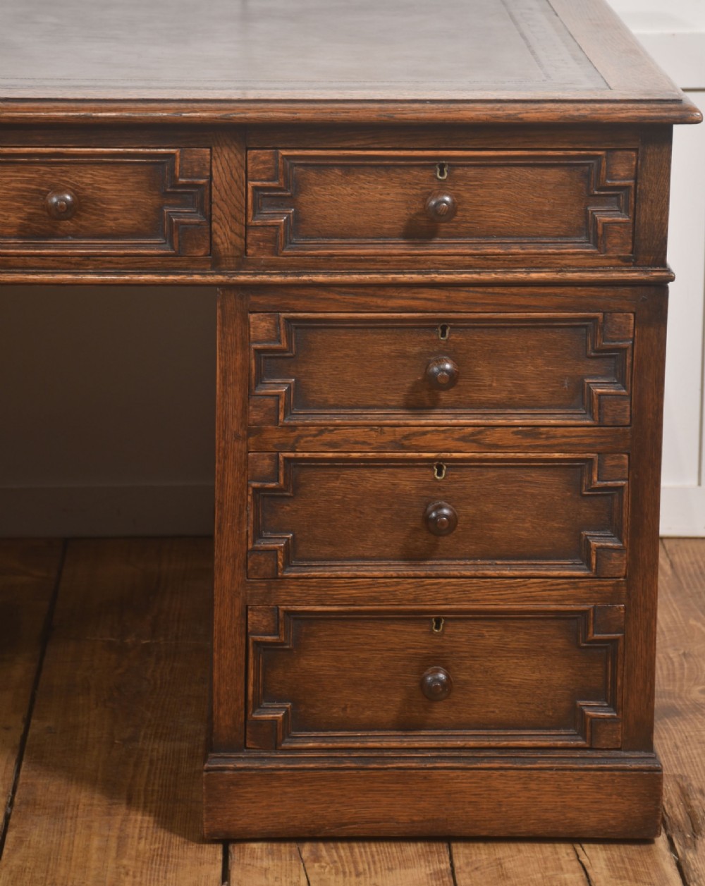 A double-pedestal antique oak partners desk featuring geometric drawer mouldings and an inset brown leather writing top. View XII