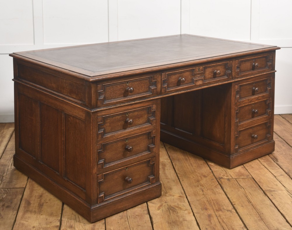 A double-pedestal antique oak partners desk featuring geometric drawer mouldings and an inset brown leather writing top. View XIII