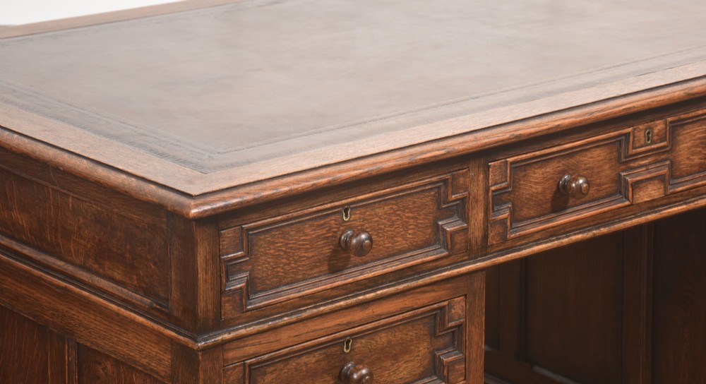A double-pedestal antique oak partners desk featuring geometric drawer mouldings and an inset brown leather writing top. View XIV