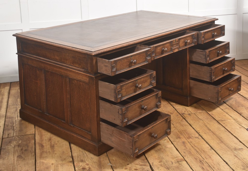 A double-pedestal antique oak partners desk featuring geometric drawer mouldings and an inset brown leather writing top. View XV